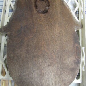 May include: A dark brown wooden hand-shaped cutting board with a circular cutout in the center.