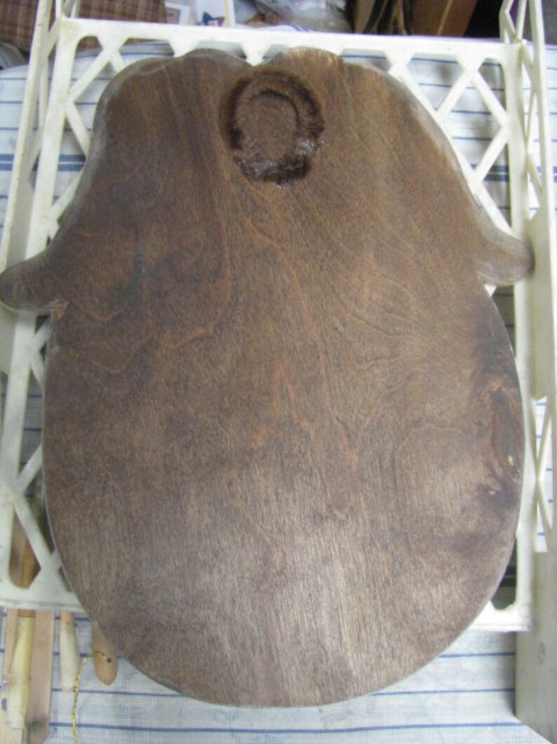 May include: A dark brown wooden hand-shaped cutting board with a circular cutout in the center.