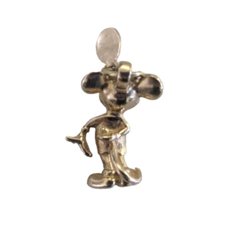 Pode incluir: Um pequeno pingente dourado em forma de rato de desenho animado. O pingente tem orelhas grandes e redondas, um rosto sorridente e segura um pequeno objeto. O pingente est&aacute; em p&eacute; e tem uma argola na parte superior para prender a uma pulseira ou colar.