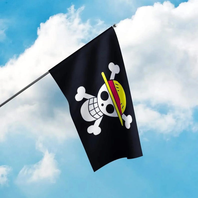 May include: A black flag with a white skull and crossbones design, featuring a yellow and red straw hat. The flag is mounted on a silver pole against a blue sky with white clouds. The flag is a symbol of the popular anime series.