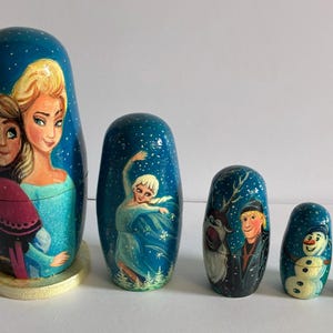 Puede incluir: Un conjunto de seis mu&ntilde;ecas rusas pintadas a mano con personajes de una popular pel&iacute;cula de animaci&oacute;n. Las mu&ntilde;ecas est&aacute;n pintadas con un fondo azul y representan varios personajes en colores vibrantes. La mu&ntilde;eca m&aacute;s grande mide unos 13 cm de altura.