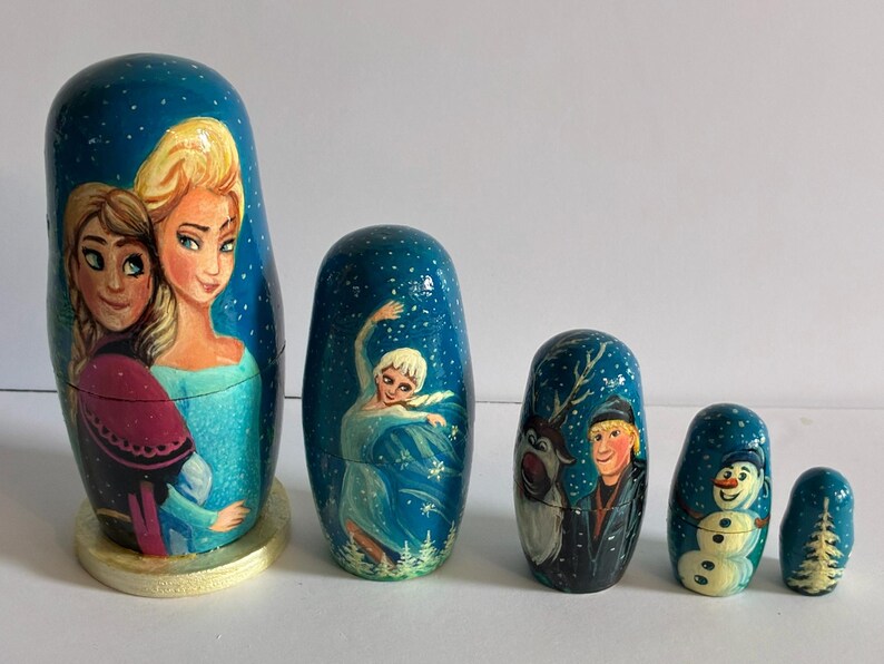 Puede incluir: Un conjunto de seis mu&ntilde;ecas rusas pintadas a mano con personajes de una popular pel&iacute;cula de animaci&oacute;n. Las mu&ntilde;ecas est&aacute;n pintadas con un fondo azul y representan varios personajes en colores vibrantes. La mu&ntilde;eca m&aacute;s grande mide unos 13 cm de altura.