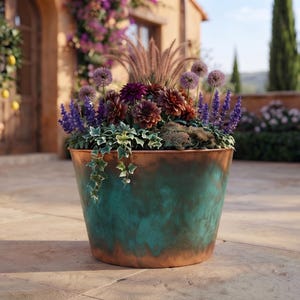 May include: A round, tapered planter with a weathered copper finish featuring a blend of teal, green, and metallic brown tones. The planter is filled with a vibrant arrangement of purple alliums, dark red dahlias, blue salvia, and trailing ivy.