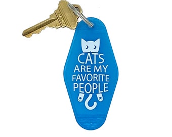 May include: Blue motel key chain with a white cat and the text "Cats are my favorite people".