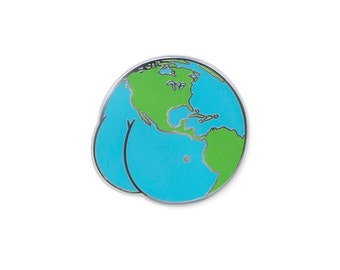 May include: A round enamel pin featuring a cartoon depiction of Earth with green continents and blue oceans. The pin has a silver border and a humorous design, with the Earth's shape resembling a pair of buttocks.