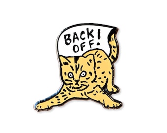 Puede incluir: Un gato amarillo con ojos negros y nariz negra sostiene un cartel blanco que dice "Back Off!" en letras negras. El gato mira al espectador con una expresión seria.
