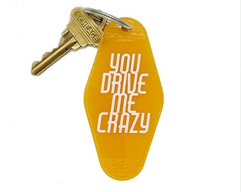 May include: A yellow motel key chain with the text "You Drive Me Crazy" in white lettering.