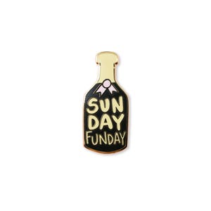 May include: Gold and black enamel pin shaped like a champagne bottle with the text "Sun Day Funday" on it.