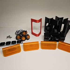 May include: An assortment of automotive lighting components, including amber lenses, black mounting brackets, a red frame, and a set of small amber lights. Also included are screws and wiring.