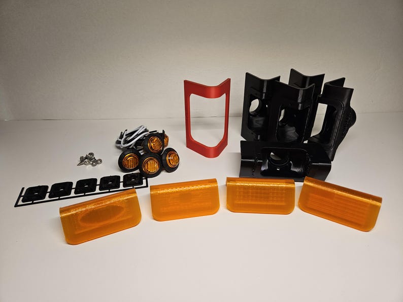May include: A collection of car lighting parts, featuring amber lenses, black mounting brackets, a red frame, and a set of small amber lights. Also includes screws and wiring.