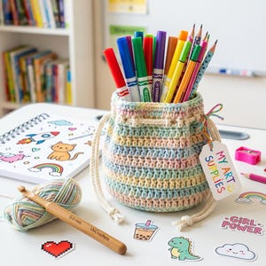 May include: A handmade, pastel-colored crochet pouch filled with colorful markers and pencils. A notebook with drawings, a ball of yarn, and a crochet hook are next to the pouch. The tag on the pouch reads "MY ART SUPPLIES".