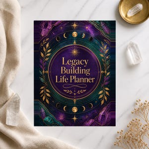 Op de afbeelding: Een rechthoekige planneromslag met een dieppaarse en blauwgroene kosmische achtergrond met gouden hemelse motieven, waaronder maanfasen en sterren. De tekst Legacy Building Life Planner is in goud in het midden van een cirkelvormig kader gedrukt.