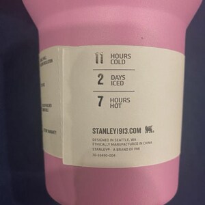 May include: A pink insulated tumbler with a white label. The label indicates the tumbler keeps contents cold for 11 hours, iced for 2 days, and hot for 7 hours. The brand is Stanley 1913.