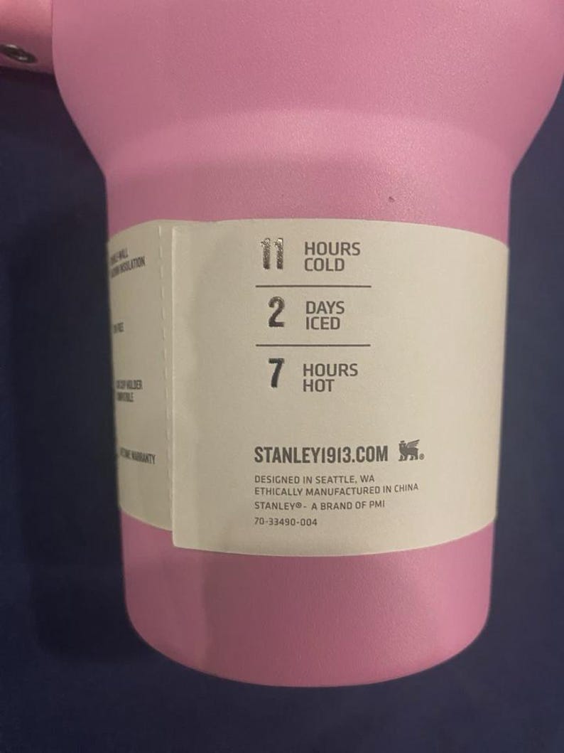 May include: A pink insulated tumbler with a white label. The label indicates the tumbler keeps contents cold for 11 hours, iced for 2 days, and hot for 7 hours. The brand is Stanley 1913.