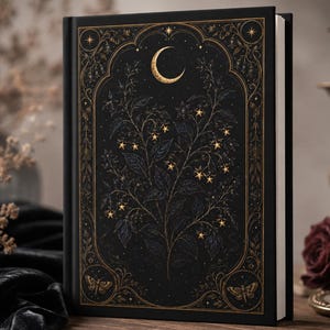 May include: A black hardcover book featuring an intricate gold foil design on the front cover. The artwork displays a central crescent moon, a botanical plant with star-shaped blossoms, and two moths framed within an ornate decorative border.