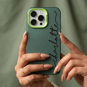 May include: A green phone case with a lime green camera ring and the text "SO COOL". The name "Charlotte" is written in a black script font. The phone case is held in a person's hands.