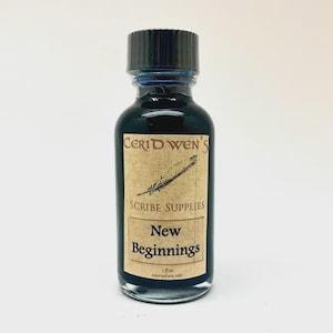 May include: A clear glass bottle filled with dark blue liquid, topped with a black ribbed cap. The label reads Ceridwen's Scribe Supplies New Beginnings with a feather illustration and the text 1 fl oz external use only.