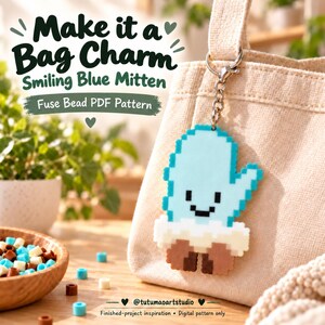 Könnte beinhalten: Ein hellblauer Bügelperlen-Handschuh-Anhänger mit lächelndem Gesicht, weißer Manschette und brauner Basis, befestigt an einer Metallkette an einer beigen Stofftasche. Text: Make it a Bag Charm, Smiling Blue Mitten, Fuse Bead PDF Pattern, @tutumaartstudio.
