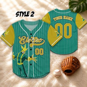Puede incluir: Camiseta de b&eacute;isbol verde y dorada con la palabra "Electro" y el n&uacute;mero "00" en la parte delantera. La camiseta tiene un gr&aacute;fico de dibujos animados de un superh&eacute;roe. La parte trasera de la camiseta tiene el texto "YOUR NAME" y el n&uacute;mero "00". Un guante y una pelota de b&eacute;isbol tambi&eacute;n est&aacute;n en la imagen.