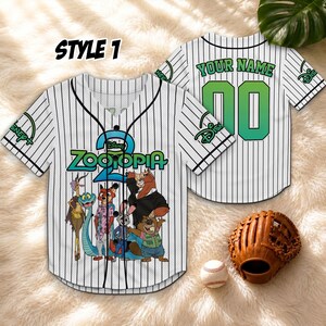 May include: White baseball jersey with black pinstripes, featuring "Zootopia" characters and the text "STYLE 1". The jersey has a button-up front and a green number "00" on the back, with "YOUR NAME" above it. A baseball glove and ball are also in the image.
