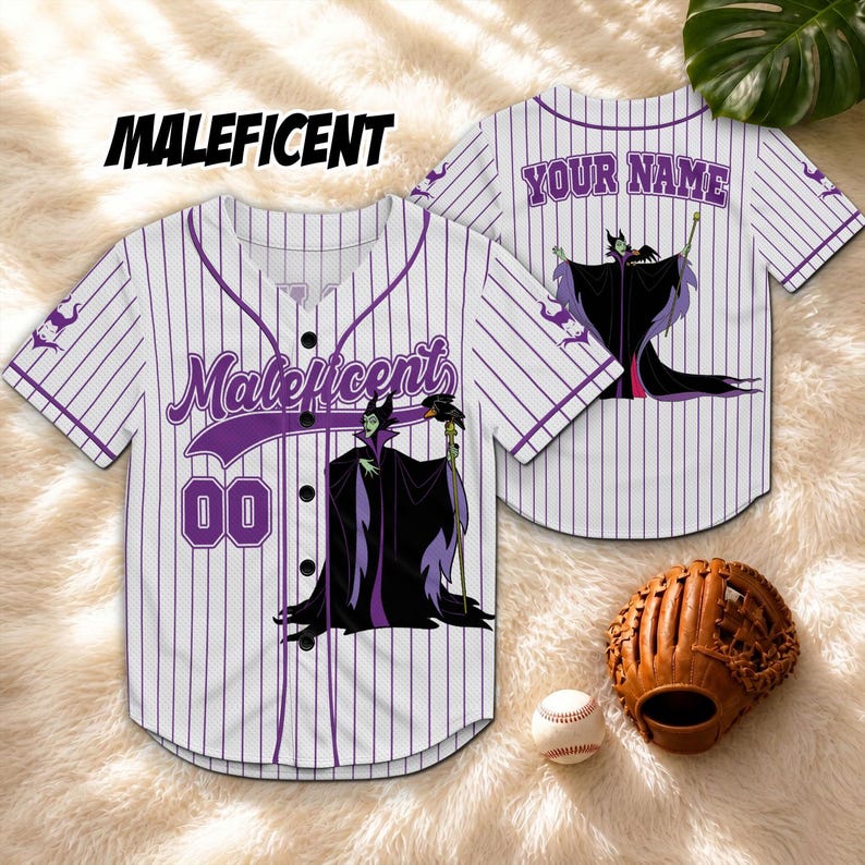 Może przedstawiać: Biała i fioletowa koszulka do baseballu w paski z napisem "Maleficent" w fioletowym skrypcie. Koszulka ma kresk&oacute;wkowy wizerunek Maleficent z przodu i z tyłu. Rękawica i piłka do baseballu znajdują się na pierwszym planie.
