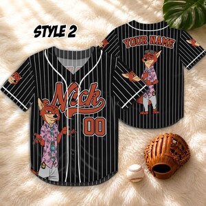 May include: Black and white pinstripe baseball jersey with the name "Nick" and the number "00" in orange. The jersey features a cartoon fox character and the text "STYLE 2". A baseball glove and ball are in the image.