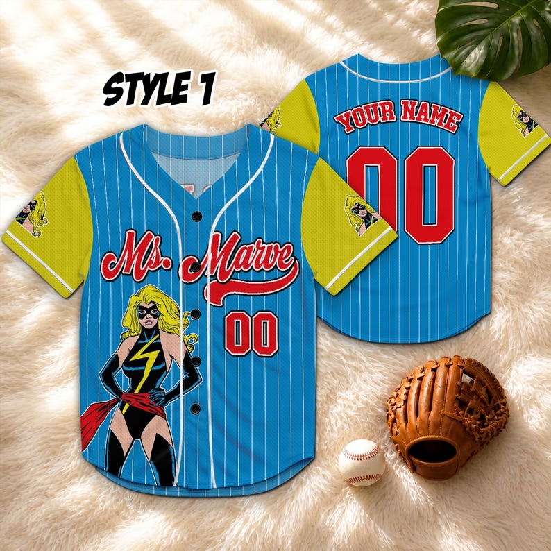 May include: Blue baseball jersey with white pinstripes, yellow sleeves, and a Ms. Marvel graphic. The jersey features the text "Ms. Marvel" and the number "00" in red. A baseball glove and ball are also visible.