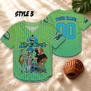May include: Green baseball jersey with vertical white stripes, featuring "Zootopia" characters and logo. The jersey has a teal neckline and sleeve trim, with the text "YOUR NAME" and the number "00" on the back. A baseball glove and ball are also in the image.