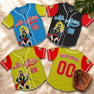 May include: Four baseball jerseys with a Ms. Marvel graphic. The jerseys are blue, black, and yellow with red and yellow accents. Each jersey has the number "00" on it. A baseball glove is also in the image.