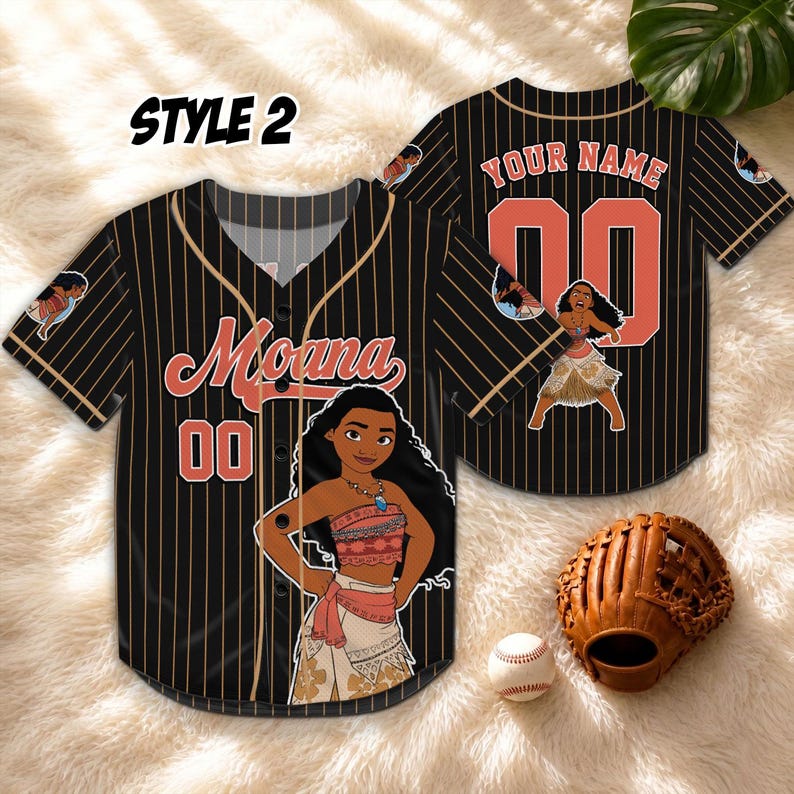 Może przedstawiać: Czarna koszulka baseballowa w paski z napisem "Moana" i numerem "00" w kolorze koralowym. Koszulka ma kresk&oacute;wkowy wizerunek Moany z przodu i z tyłu, z napisem "YOUR NAME" z tyłu.