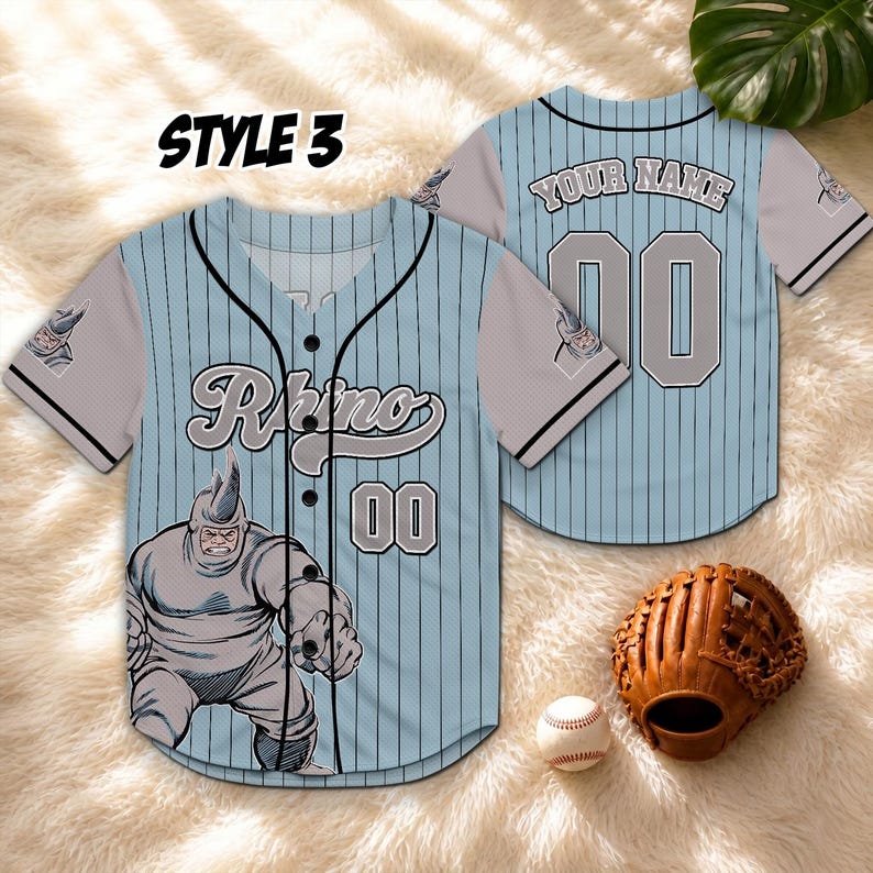 May include: Light blue baseball jersey with black pinstripes, featuring a Rhino character graphic and the number 00. The jersey has grey sleeves and the text "Rhino" across the chest. A baseball glove and ball are also visible.