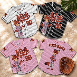 May include: Four baseball jerseys with a cartoon fox design. The jerseys are white with black pinstripes, black with white pinstripes, and pink with white pinstripes. Each jersey features the name "Nick" and the number "00". A baseball glove is also present.