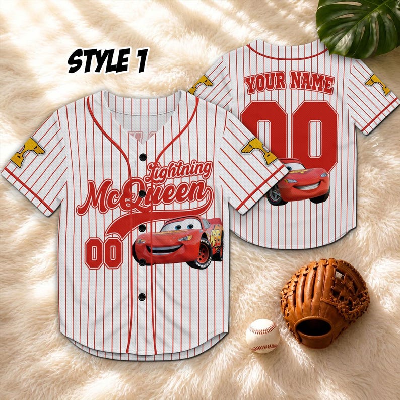 Puede incluir: Camiseta de b&eacute;isbol a rayas blancas y rojas con "Lightning McQueen" y "00" impresos en la parte delantera. La parte trasera muestra "YOUR NAME" y el n&uacute;mero "00". Tambi&eacute;n hay un guante y una pelota de b&eacute;isbol.