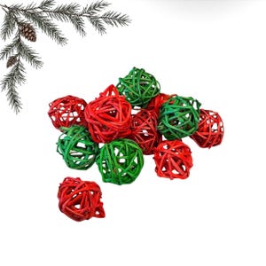 Pode incluir: Uma coleção de ornamentos decorativos esféricos feitos de material de vime trançado, apresentando uma mistura vibrante de cores sólidas vermelhas e verdes. Os itens estão dispostos em um grupo solto, exibindo uma estrutura de treliça.