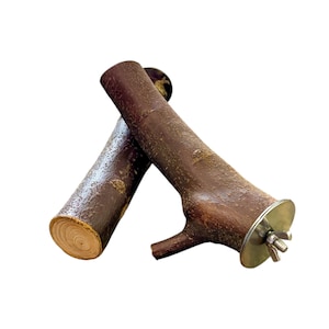 May include: Two cylindrical brown wooden branches with textured bark. One branch features a small side twig and a circular metal washer with a threaded bolt and wing nut attached to one end, while the other branch shows a light-colored wood grain cross-section.