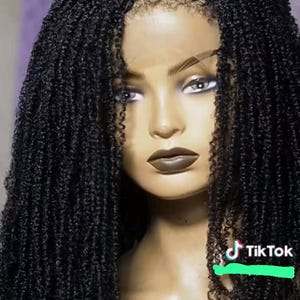 Può includere: Una parrucca nera con lace front caratterizzata da lunghe micro-trecce strettamente avvolte e una riga centrale definita. La consistenza dei capelli è uniforme e densa, ricadendo sulle spalle di una testa di manichino con rossetto scuro.