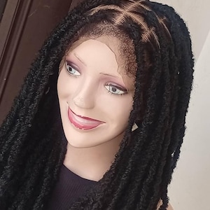 Puede incluir: Una peluca negra con rastas falsas, peinada en una cabeza de maniquí. La peluca presenta un frente de encaje y una línea de cabello de aspecto natural. Las rastas son gruesas y texturizadas, creando un aspecto completo y voluminoso.