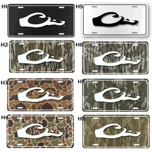 May include: License plates with a white logo on various backgrounds. The backgrounds include black, white, and camouflage patterns in shades of brown, green, and gray. The logo is a stylized duck.