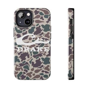 K&ouml;nnte beinhalten: Eine Smartphone-H&uuml;lle mit einem Tarnmuster in Braun-, Gr&uuml;n- und Beiget&ouml;nen. Die H&uuml;lle zeigt ein wei&szlig;es grafisches Logo einer Entenkopf-Silhouette &uuml;ber dem wei&szlig;en Schriftzug DRAKE. Das Design ist sowohl von der R&uuml;ckseite als auch von der Seite zu sehen.