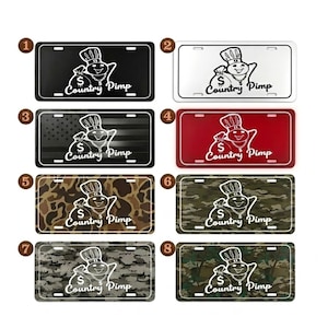 May include: Eight rectangular license plates featuring a white graphic of a chef holding a money bag with a dollar sign, wearing a chain, and the text Country Pimp. Designs include solid black, white, red, American flag, and various camouflage patterns.