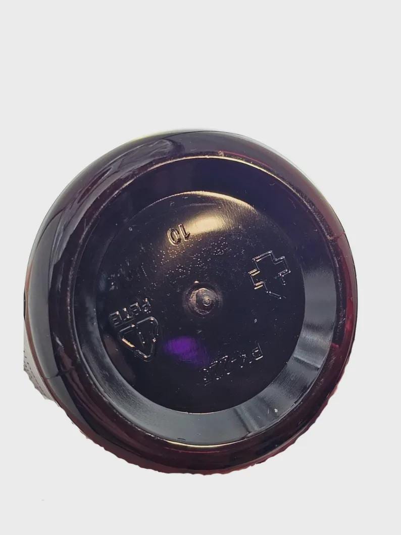 May include: Close-up of the base of a dark brown plastic bottle. The circular base has embossed markings, including the number "10" and the letters "PETE". The bottle's surface reflects light, highlighting its shape.
