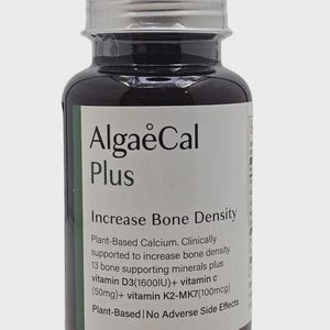 May include: A dark brown supplement bottle with a silver cap and a white label. The label reads "AlgaeCal Plus" and "Increase Bone Density." It lists ingredients including vitamin D3 and vitamin C. The bottle is plant-based and has no adverse side effects.