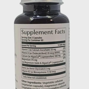 May include: A dark brown supplement bottle with a silver lid. The label displays "Supplement Facts" and lists ingredients like Vitamin C, D, and K2. The bottle contains 60 servings of 2 capsules each.