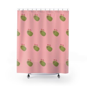 Puede incluir: Cortina de ducha rosa con un patrón repetido de aceitunas verdes, cada una con un corazón rojo y el texto "Olive You". La cortina está hecha de un material suave y opaco y cuelga de una barra de metal.