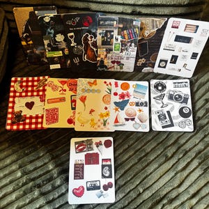 May include: A collection of decorative cards with various designs. Some cards feature collages with images of a couple, a wine glass, and a bat. Other cards have images of a camera, a sailboat, and a heart-shaped Coca-Cola logo.