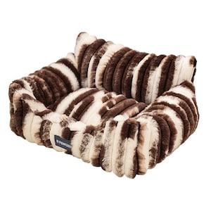 Puede incluir: Una cama rectangular para mascotas con un estampado de cebra de piel sintética en marrón y crema. La cama tiene un borde elevado y un interior suave y afelpado. La etiqueta "R PAWSZEB" es visible en el lateral.
