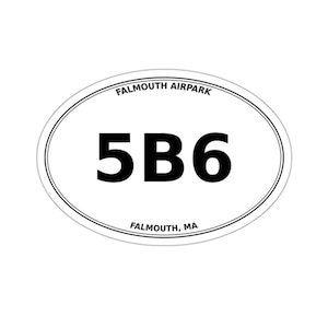 May include: An oval-shaped white sticker with a thin black border. The text "FALMOUTH AIRPARK" is printed in black along the top curve, and "FALMOUTH, MA" is along the bottom. The large black alphanumeric characters "5B6" are centred.