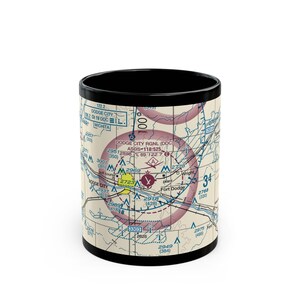 May include: Black and white ceramic mug featuring a detailed aviation sectional chart design. The mug has a black interior and rim, with the chart wrapping around the exterior. The chart includes text such as "Dodge City" and "Wichita".
