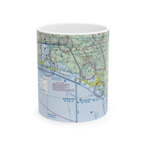 May include: White ceramic mug featuring a detailed aviation sectional chart design. The map includes various navigational elements, text, and color-coded areas. The mug has a cylindrical shape and a white interior.