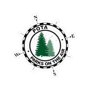 May include: A white sticker featuring a compass design with the text "POTA" at the top and "Parks on the Air" at the bottom. Two green pine trees are in the center. The compass points are labeled N, E, S, and W.